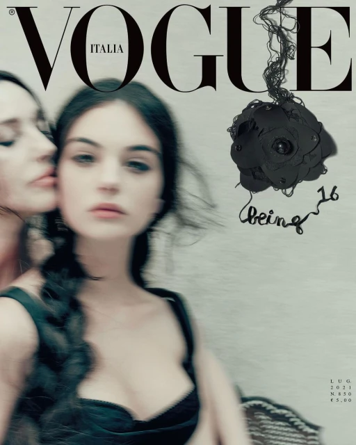 Vogue Italia cover featuring two young women with dark hair in black tops, one embracing the other with a shallow depth of field.