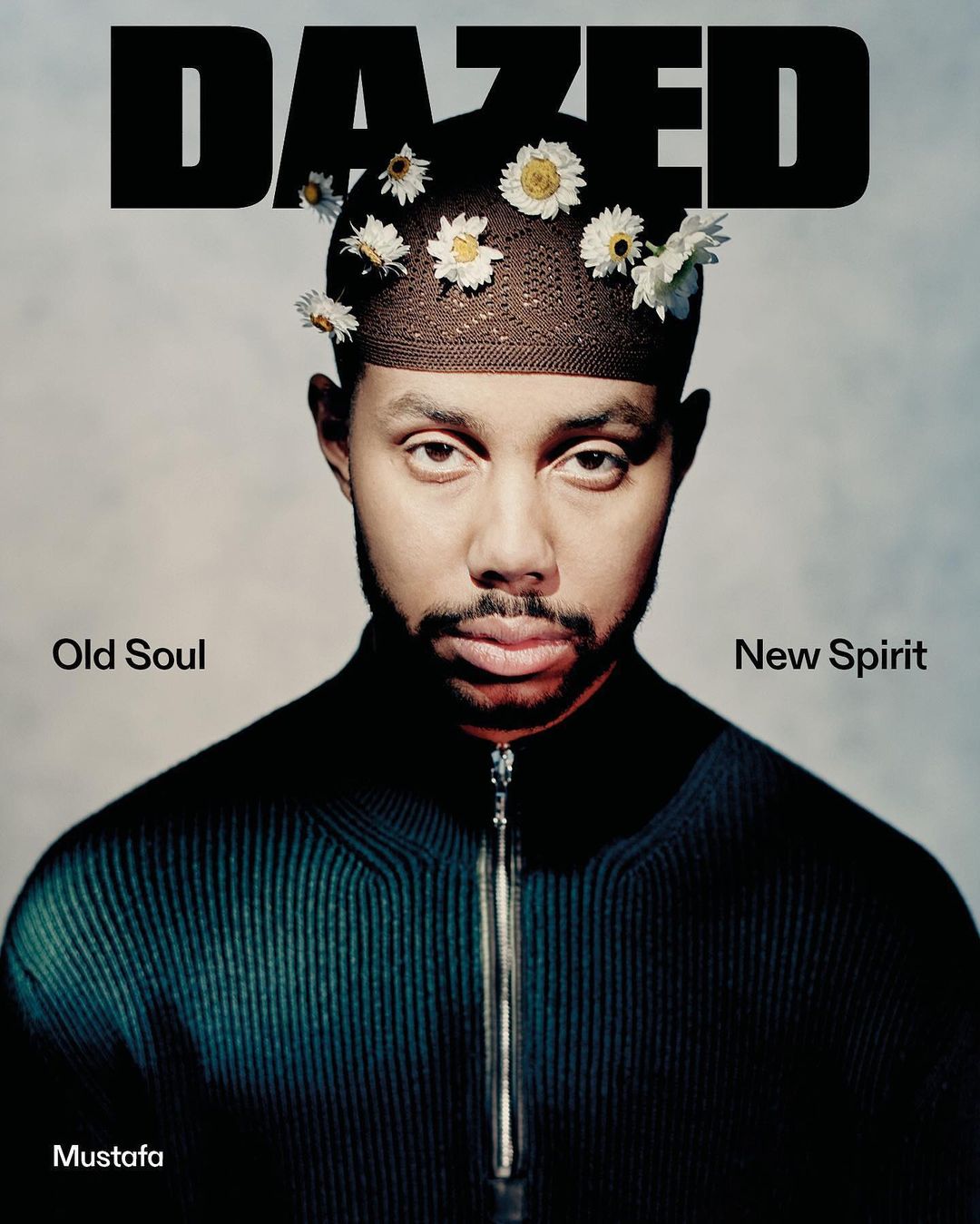 Portrait of a black male with flowers in his hair in front of a solid background. Dazed magazine cover. Style is editorial.