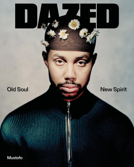 Portrait of a black male with flowers in his hair in front of a solid background. Dazed magazine cover. Style is editorial.