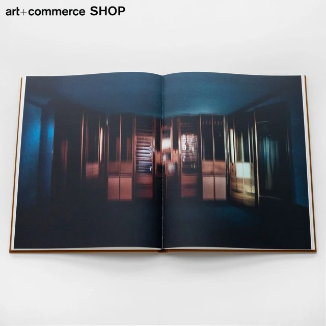 Open book featuring an interior photograph showcasing a room with dividers under dim, bluish lighting, creating a moody ambiance.