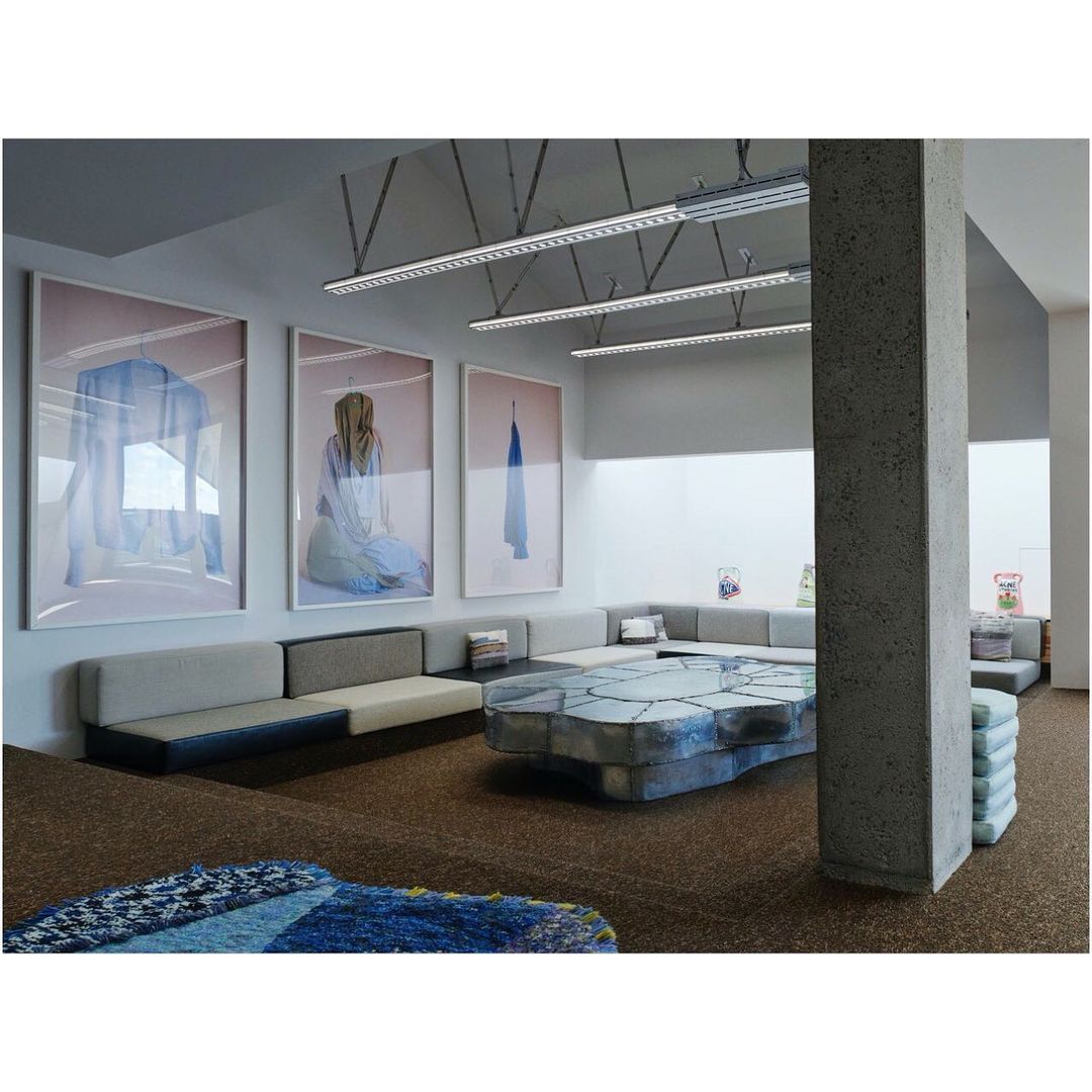 Gallery space with abstract art, modular sofas, and a sculptural table, creating a modern, inviting lounge or waiting area.