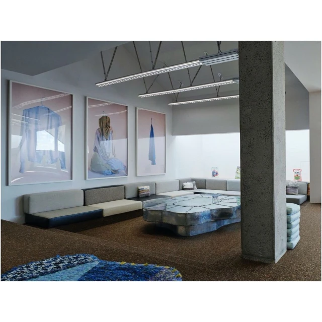 Gallery space with abstract art, modular sofas, and a sculptural table, creating a modern, inviting lounge or waiting area.