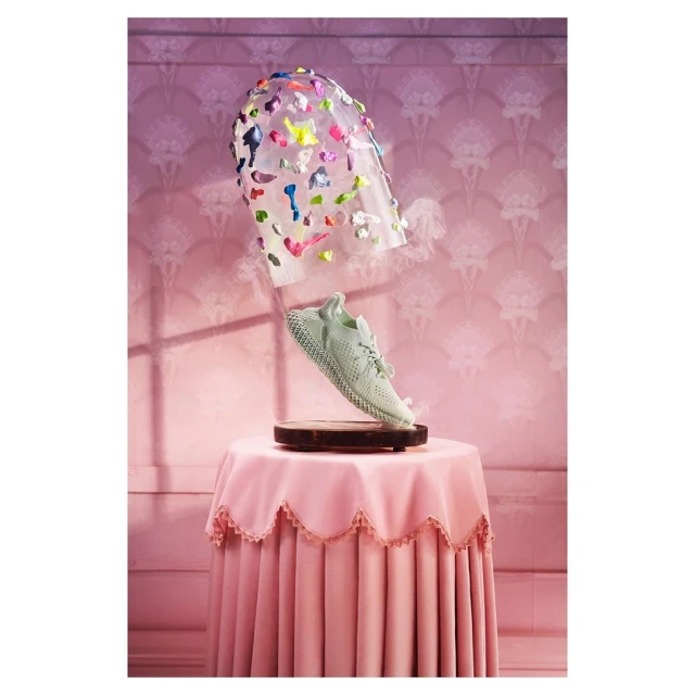 Conceptual image of a light green sneaker displayed on a small table under a transparent plastic dome with colorful accents.
