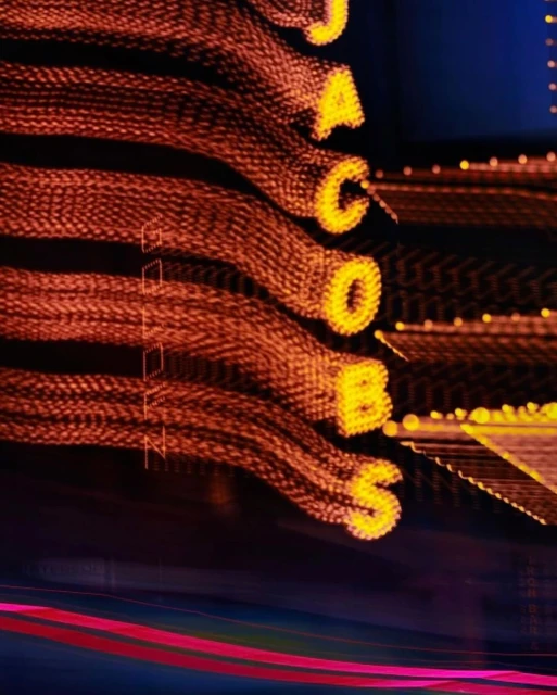 Illuminated JACOBS sign glows with blurred motion effect against dark background, creating a dynamic visual for entertainment.
