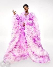 Lil Nas X wearing a voluminous pink ruffled gown against a clean white background