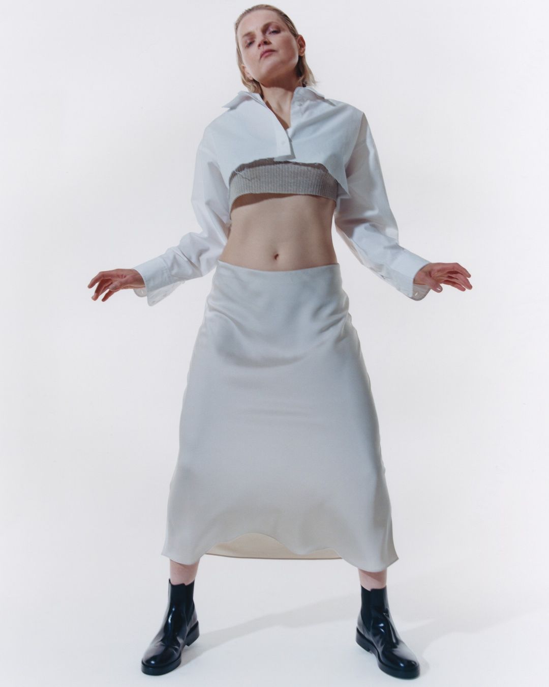 Woman in white shirt and skirt posing in a photo studio with soft, diffused lighting, showcasing fashion and studio photography.
