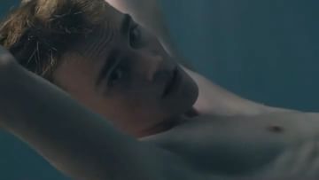 Young man submerged in water, his face visible as he floats serenely, creating a tranquil and captivating underwater portrait.