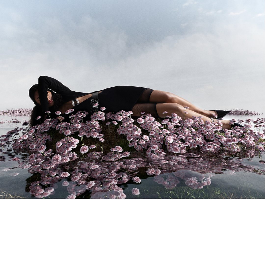Model lying on a mound of small pink flowers surrounded by water under an overcast sky, photographed by Pascal Schonlau.