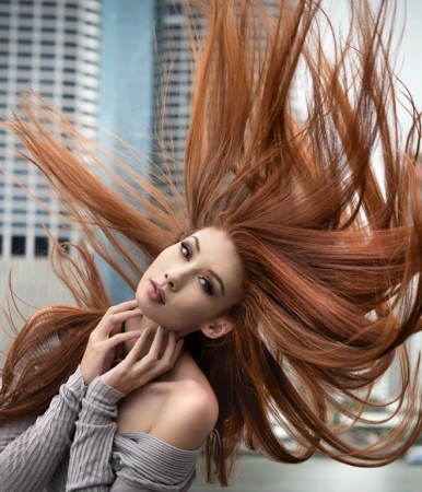 Woman with long red hair tossing in the air while wearing an off-shoulder ribbed top outdoors in Sydney, photographed by Gary Bell.