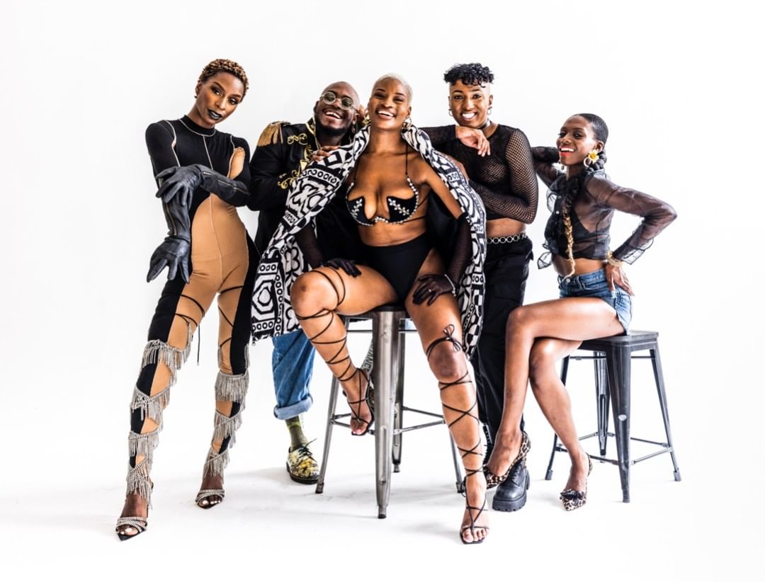 Five fashionably dressed young adults in a white studio setting, posing and smiling, showcasing diverse outfits, makeup, and hairstyles.