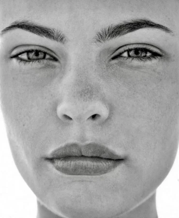 Monochrome portrait of a woman's face featuring symmetrical composition and soft, diffused lighting emphasizing her natural skin texture.