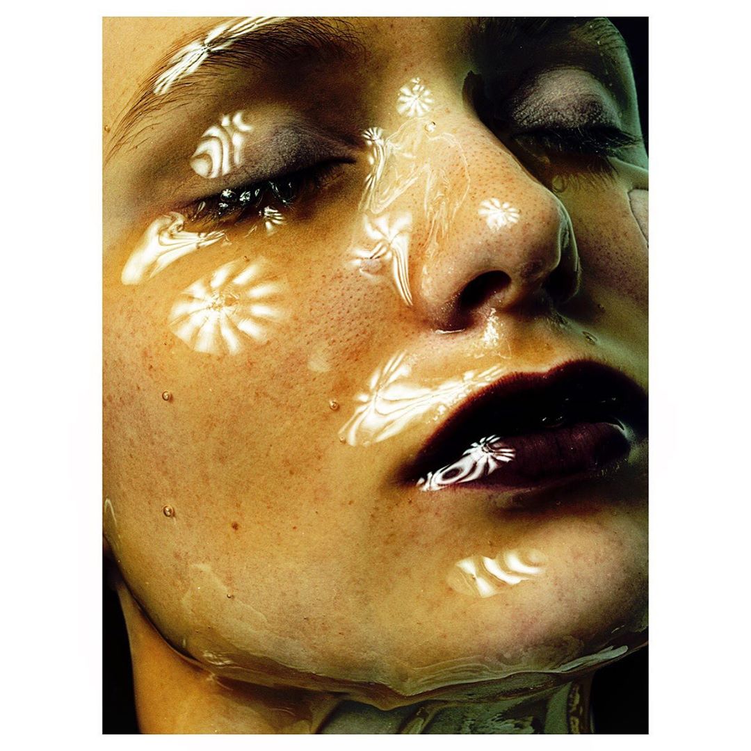 Close-up of an adult female face with eyes closed and dramatic makeup and patterned lighting creating a beauty or fashion portrait.
