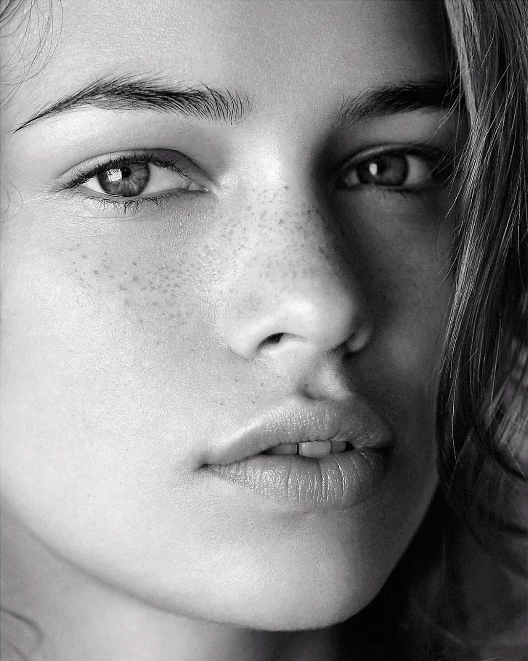 Close-up black and white portrait of a woman with freckles and dark hair by Patric Shaw