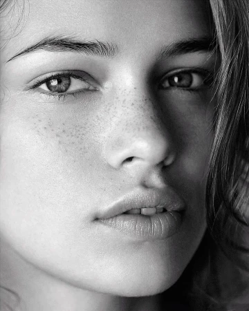 Close-up black and white portrait of a woman with freckles and dark hair by Patric Shaw