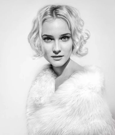 Black and white portrait of a blond woman wearing a fur stole, close-up studio shot with shallow depth of field and soft lighting.
