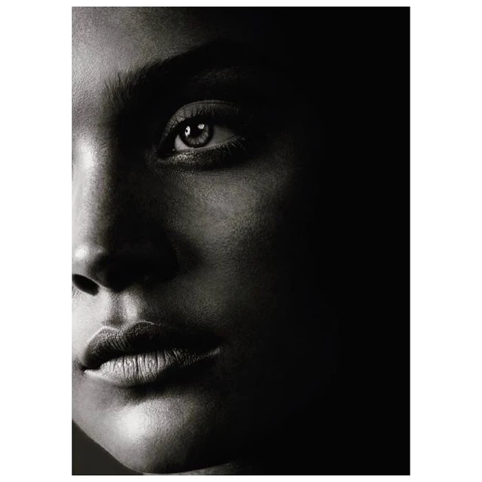 Close-up black and white portrait of a person face with dramatic lighting in a dark setting