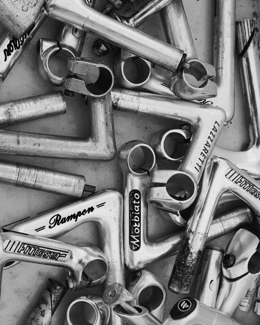 Monochrome image showcasing a collection of vintage bicycle stems, stacked closely, creating an abstract pattern of metallic textures and forms.