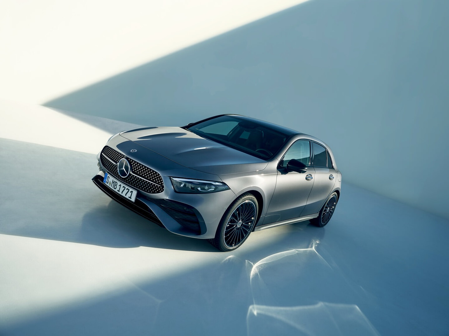Sleek grey Mercedes-Benz A-Class hatchback showcased in a studio setting with patterned shadows enhancing its modern design.