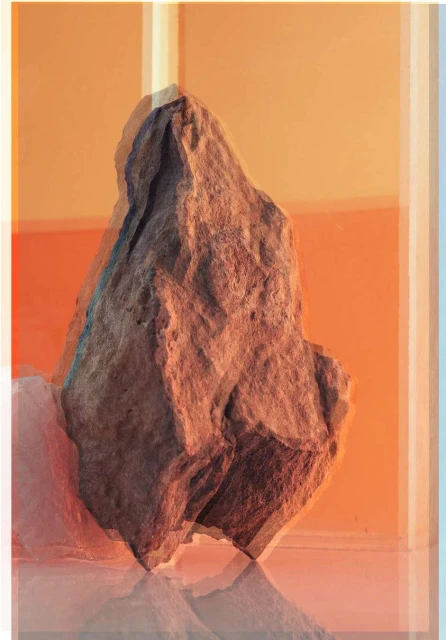 Studio shot of a textured brown rock on a glossy surface, illuminated by warm, bright lighting against an orange background.