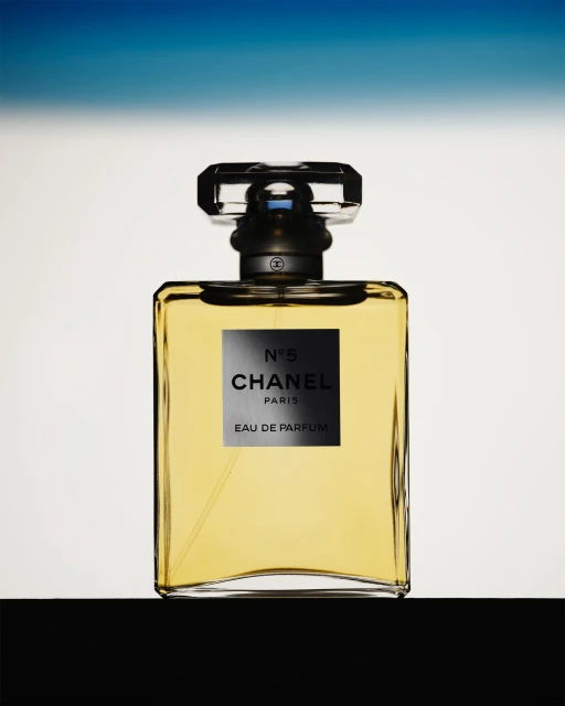 Chanel No. 5 perfume bottle presented against a gradient background. The bottle features a clear glass design and a black label.
