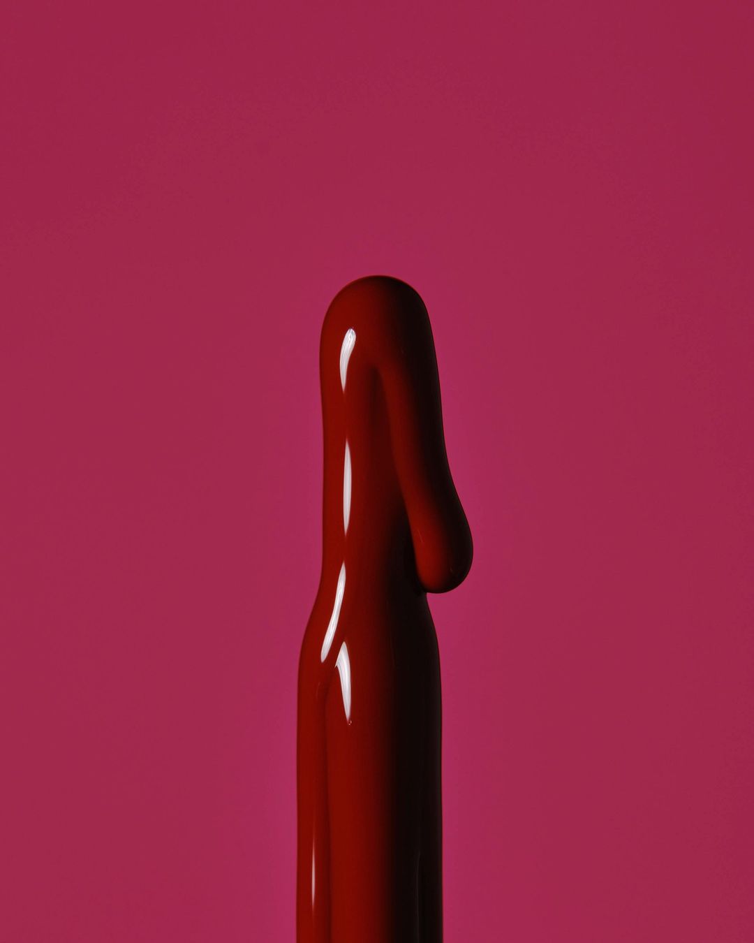 Close-up of a glossy, viscous fluid in a deep red hue against a solid background of matching color, creates a bold, monochromatic effect.