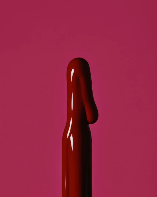 Close-up of a glossy, viscous fluid in a deep red hue against a solid background of matching color, creates a bold, monochromatic effect.