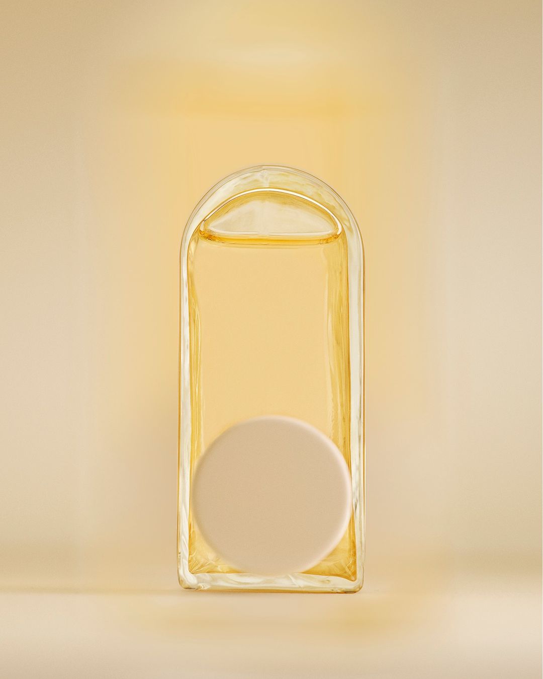 Minimalist skincare product in a clear glass bottle with a round cap against a soft gradient beige background. Beauty product shot.