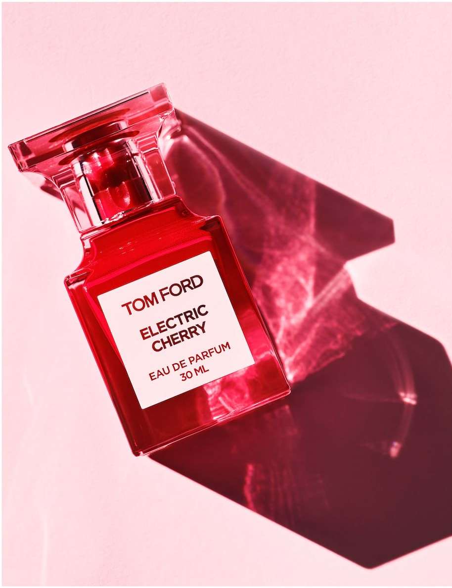 Elevated studio shot of red Tom Ford Electric Cherry Eau de Parfum 30ml bottle casting angled shadow on pink background.
