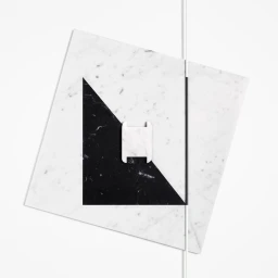 Geometric still life composition featuring layered white and black marble slabs on a white background.