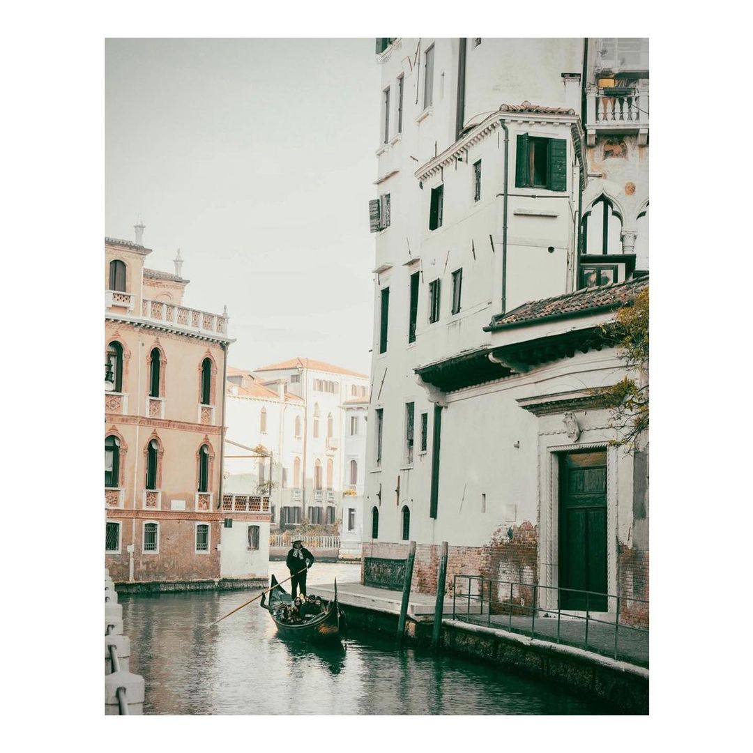 Gondola ride in Venice, Italy with a gondolier steering a traditional Venetian boat along a canal between historic buildings.