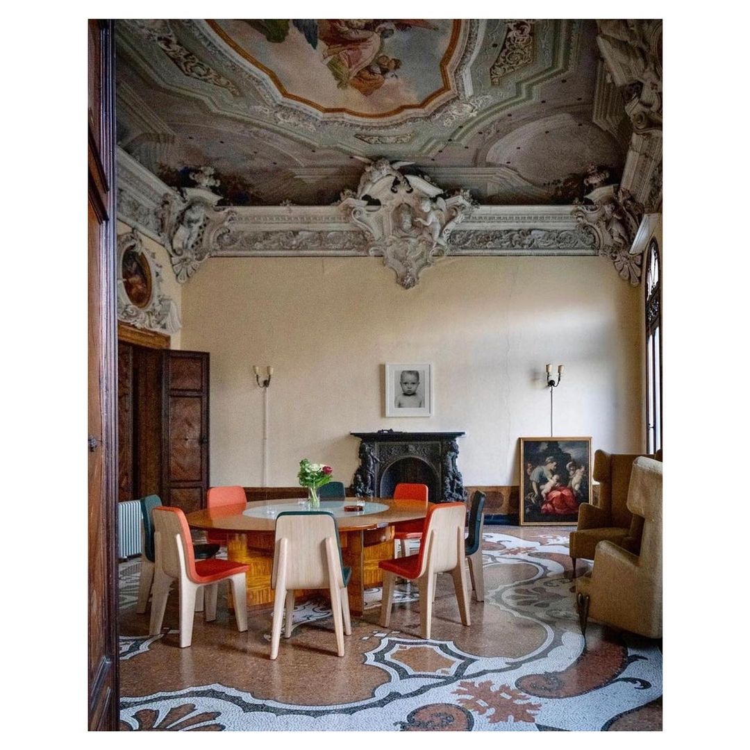 Ornate dining room interior with round table, chairs, and painted ceiling in a vintage style, showcasing classical architectural details and design.