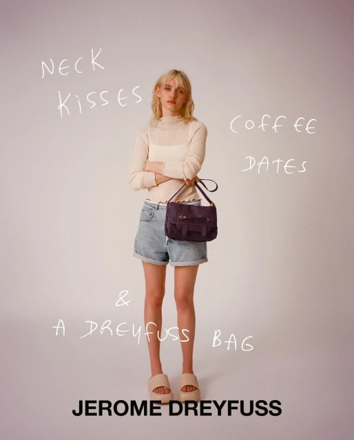 Fashion shot of a woman in denim shorts holding a satchel bag, posing indoors against a plain background with handwritten text overlay.