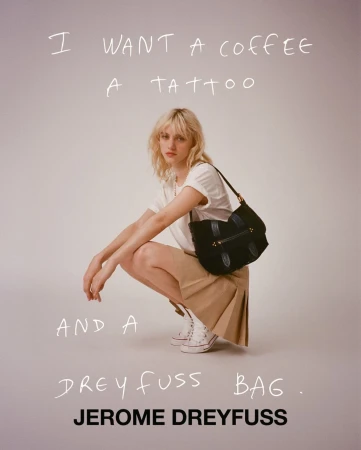 Blonde woman wearing white t-shirt and pleated skirt crouching against a light grey background with handwritten text