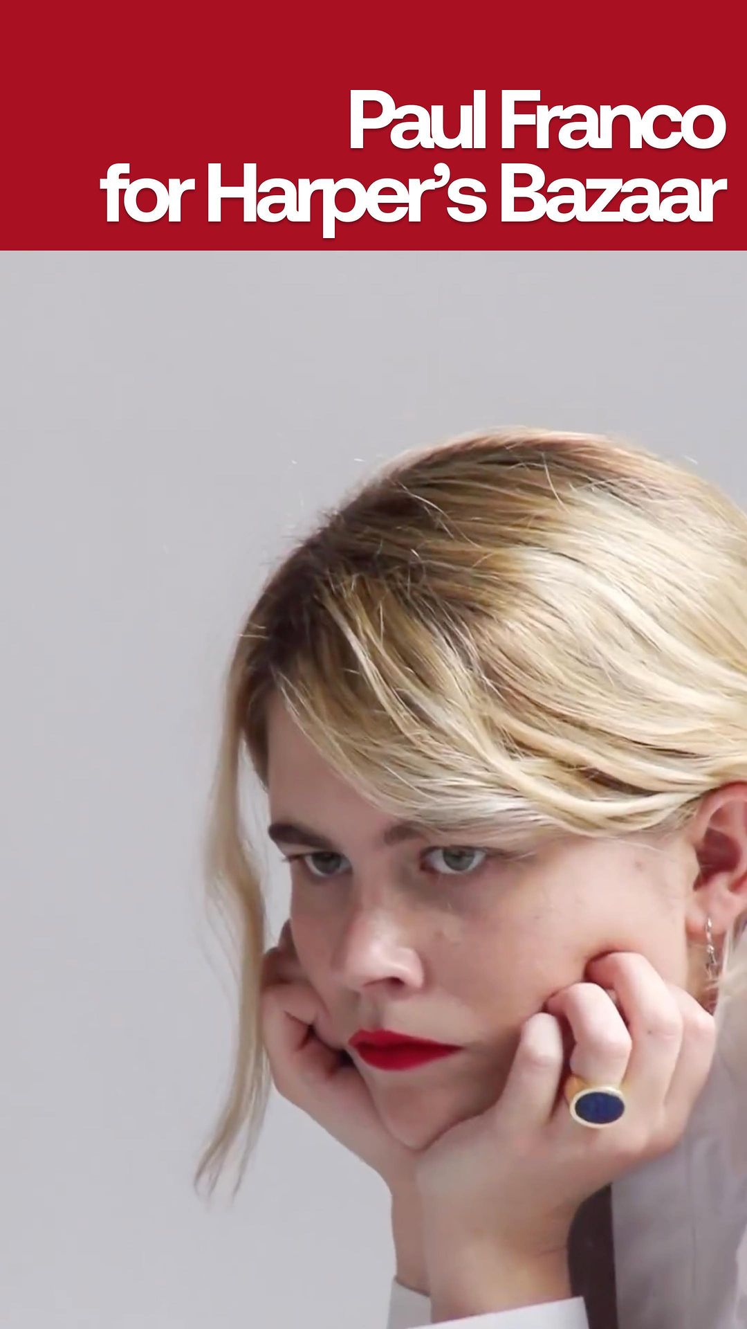 Close-up portrait of a young woman with blonde hair and red lipstick resting her face in her hands, with text above.