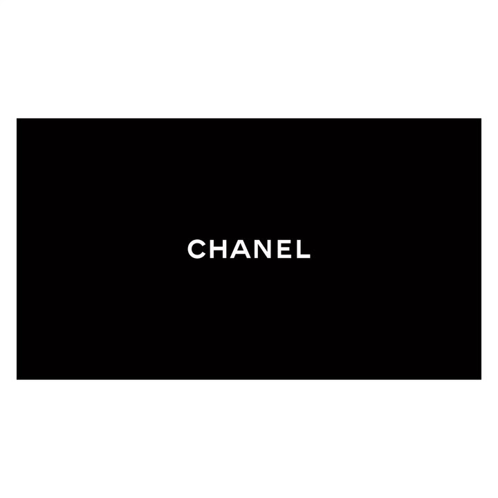 A striking close-up of the word "CHANEL" in bold, white capital letters against a solid black background.