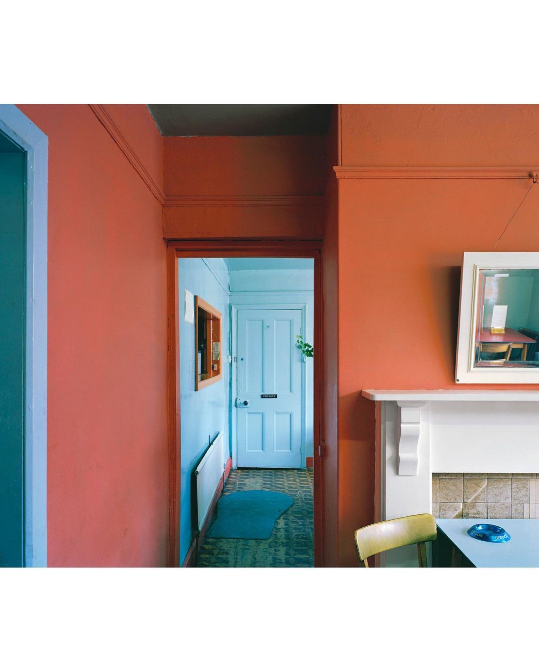 Hallway view with colorful walls, a white door leading to another room, and vintage-style furniture and decor.