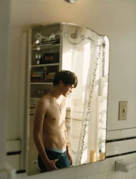 Shirtless young man wearing jeans reflected in a decorative bathroom mirror photographed by Paul Jasmin