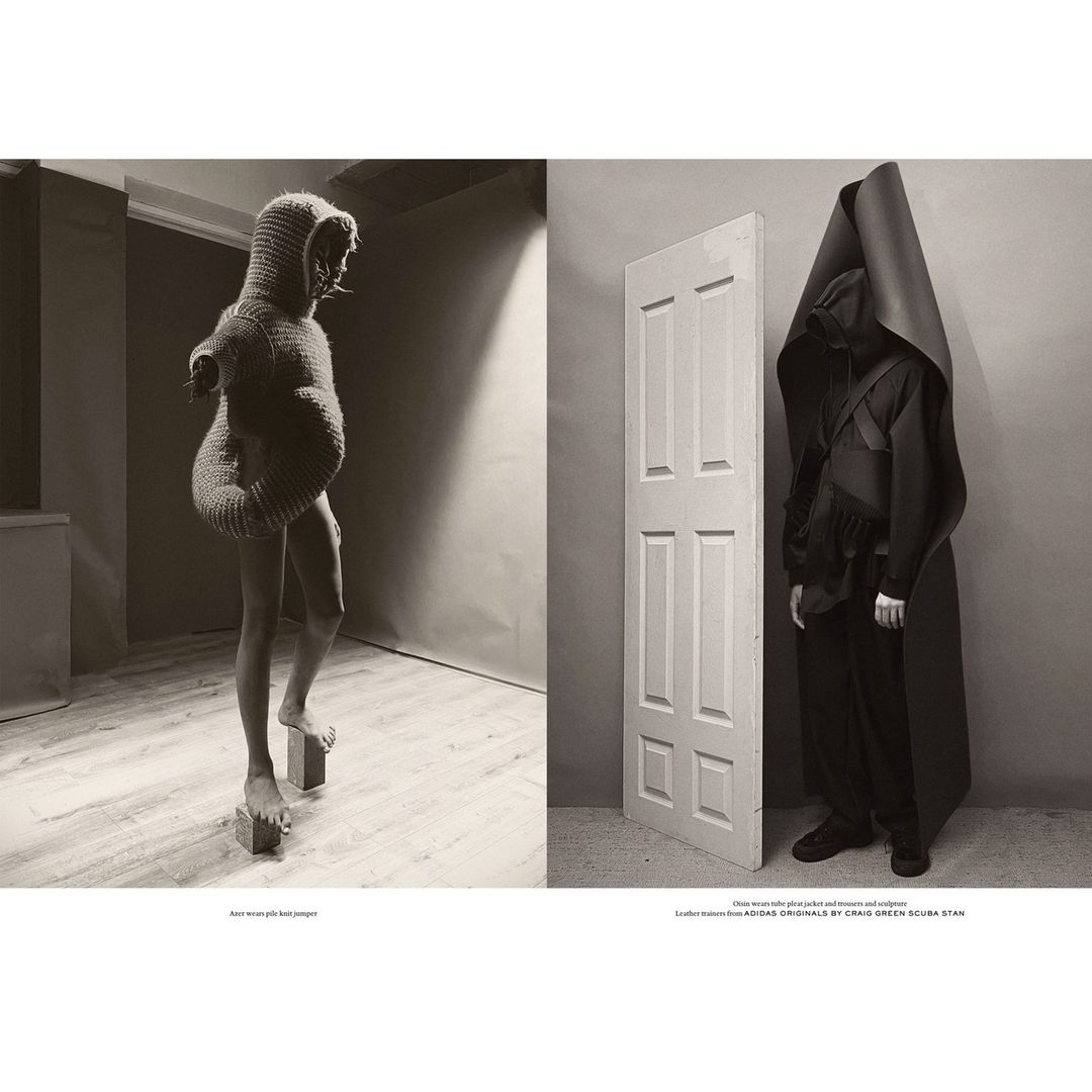 Sepia-toned studio diptych of two figures in sculptural knitwear and dark hooded outerwear, standing on platforms and next to a door.