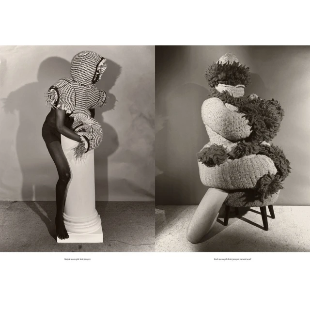 Two figures in unique knitted fashion, one standing on a column, the other seated, in a studio setting with neutral backdrop and soft lighting.