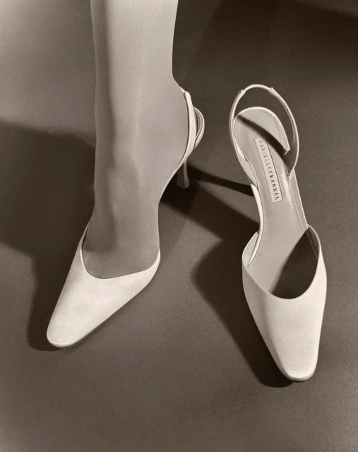 Sepia-toned image of a woman's lower leg and foot in a slingback high heel shoe. Next to it sits another high heel shoe.