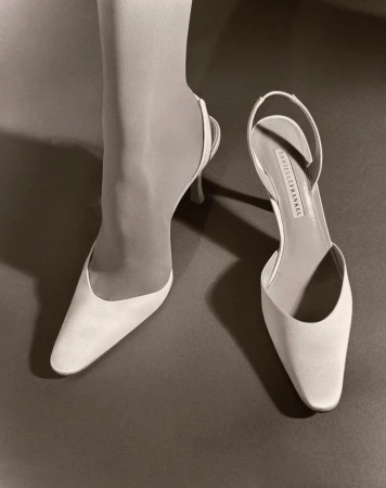 Sepia-toned image of a woman's lower leg and foot in a slingback high heel shoe. Next to it sits another high heel shoe.
