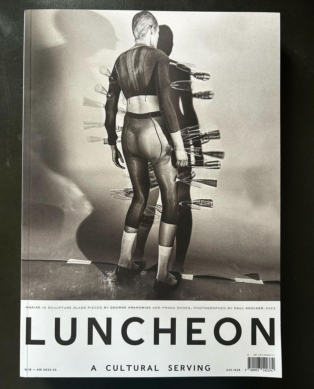 Magazine cover featuring a model in a full bodysuit with a shadow and unusual object attachments, set against a muted backdrop.