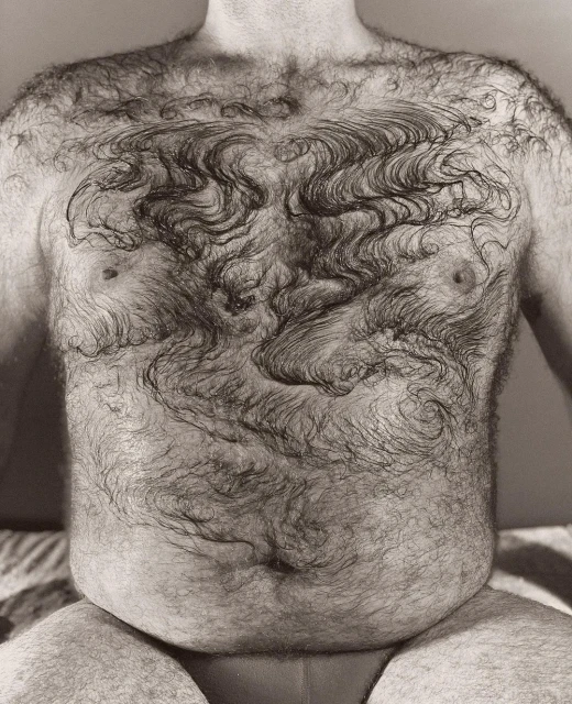 Monochrome, close-up shot of a Caucasian adult male's torso, densely covered in hair, photographed in a photo studio with soft lighting.