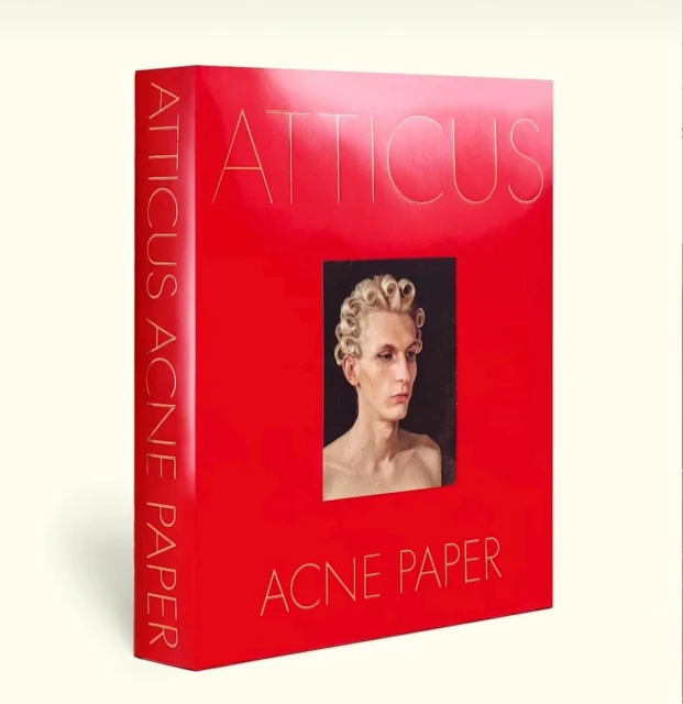 Red book cover of Acne Paper magazine, featuring a portrait of a person with a blonde curly wig. The text reads: 'Atticus, Acne Paper'.