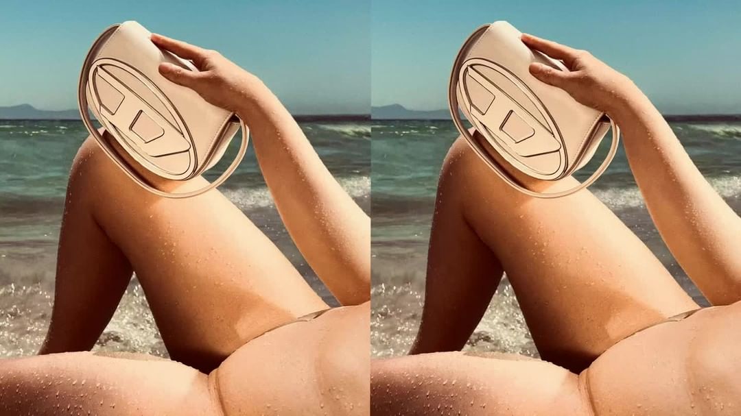 Fashion shot of a woman on a beach, holding a beige Diesel handbag, featuring sand, waves, and clear blue sky, creating a summery aesthetic.