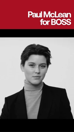 Monochrome portrait of a person wearing a dark jacket and turtleneck against a plain background
