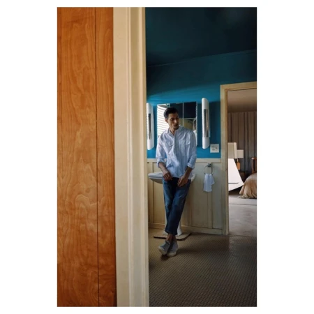 Man leaning against sink in blue and white bathroom by photographer Paul Mclean