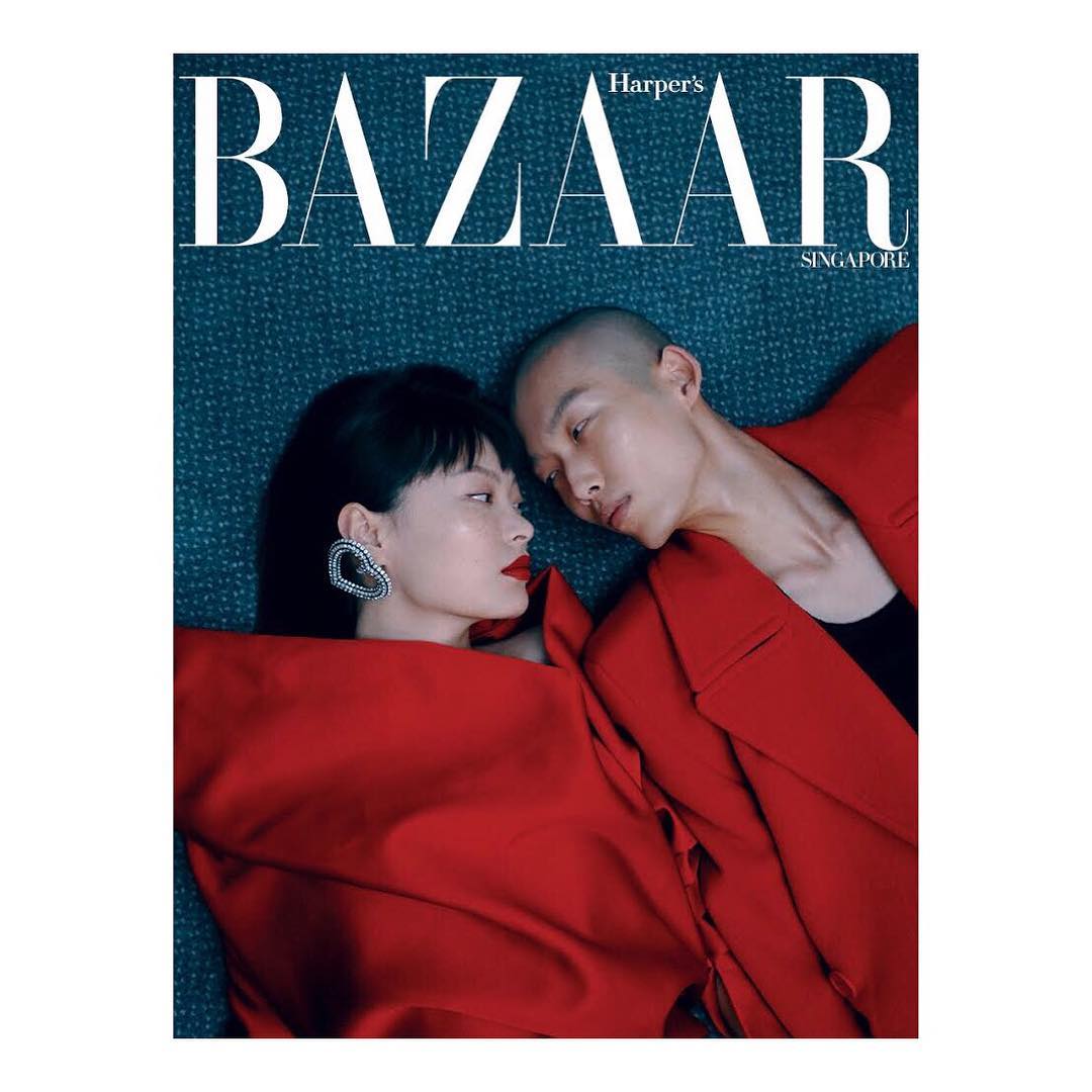 Harper's Bazaar Singapore magazine cover featuring two models in red outfits, one with short black hair, the other with a shaved head.