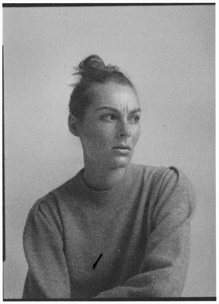 Monochrome portrait of an adult woman with an introspective expression, styled in a casual sweater against a plain backdrop.