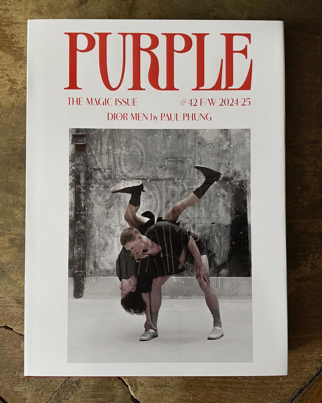 Magazine cover with two male models striking a dynamic pose against a textured wall, promoting Purple magazine's Magic Issue for F/W 2024-25.